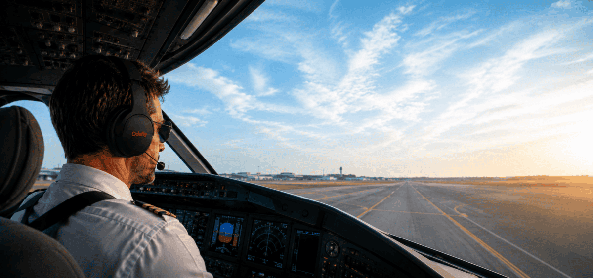Pilota in cabina di aereo durante il decollo al tramonto.